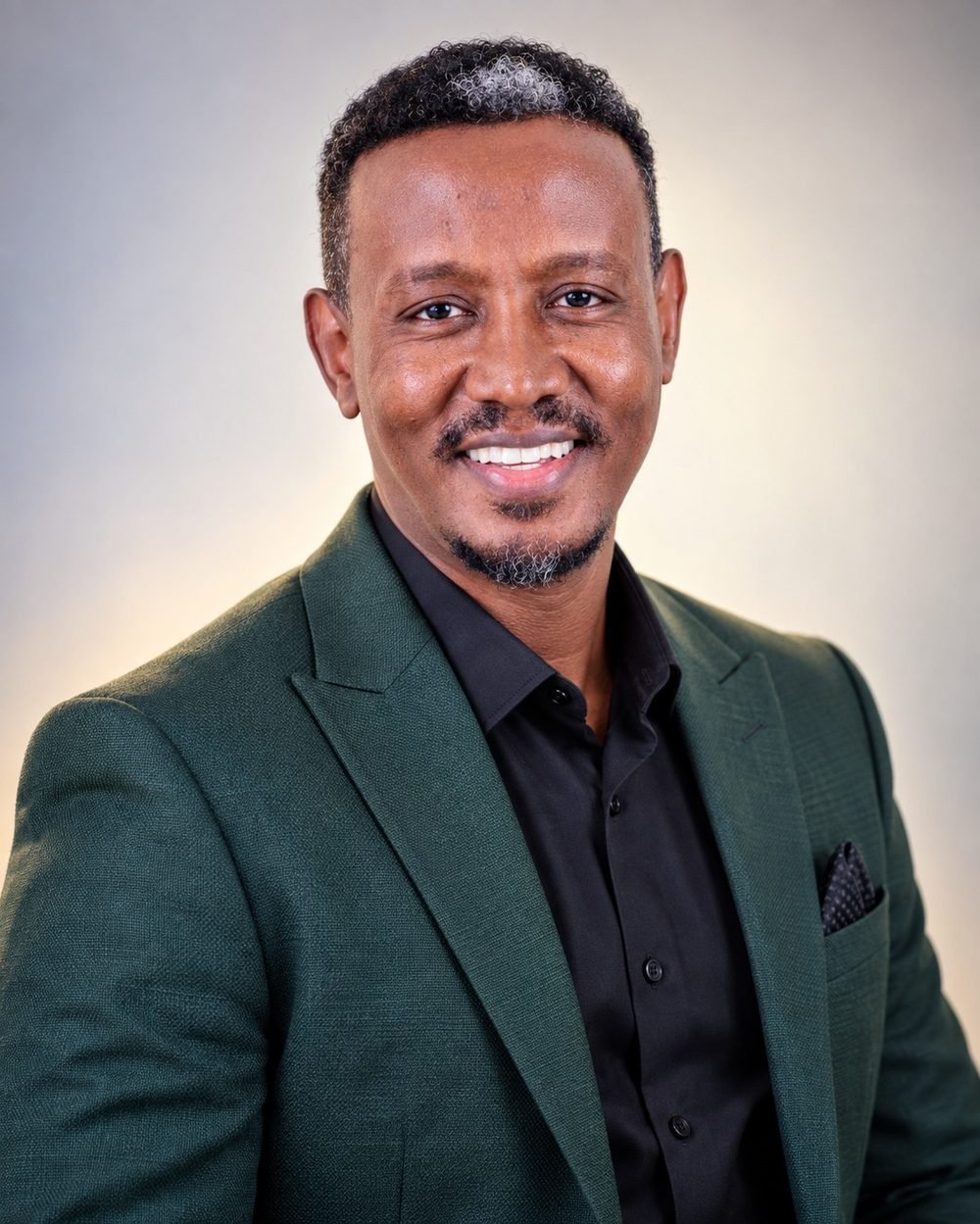Aklilu Habtemichael, standing with arms folded, smiling